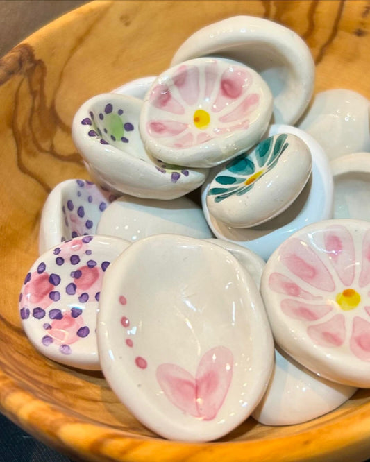 Sassi dentro una ciotola di legno d'olivo, decorati a fiori, cuori e pois.