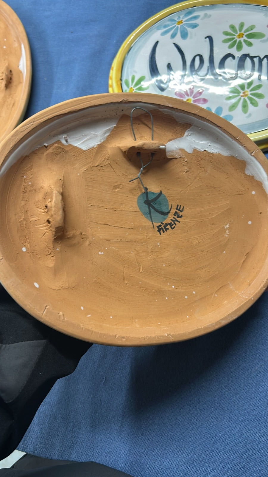 Il retro di una targa: la terracotta grezza e il gancio per appenderla.