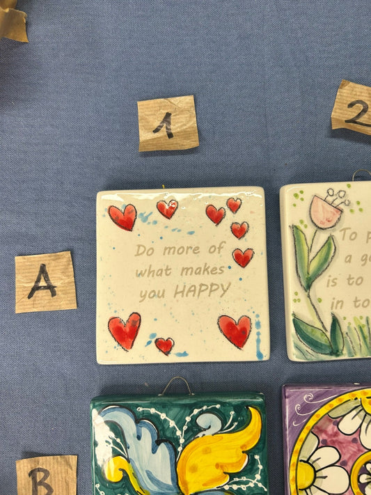Due mattonelle appese, una con i cuori rossi e la scritta «Do more of what makes you happy».