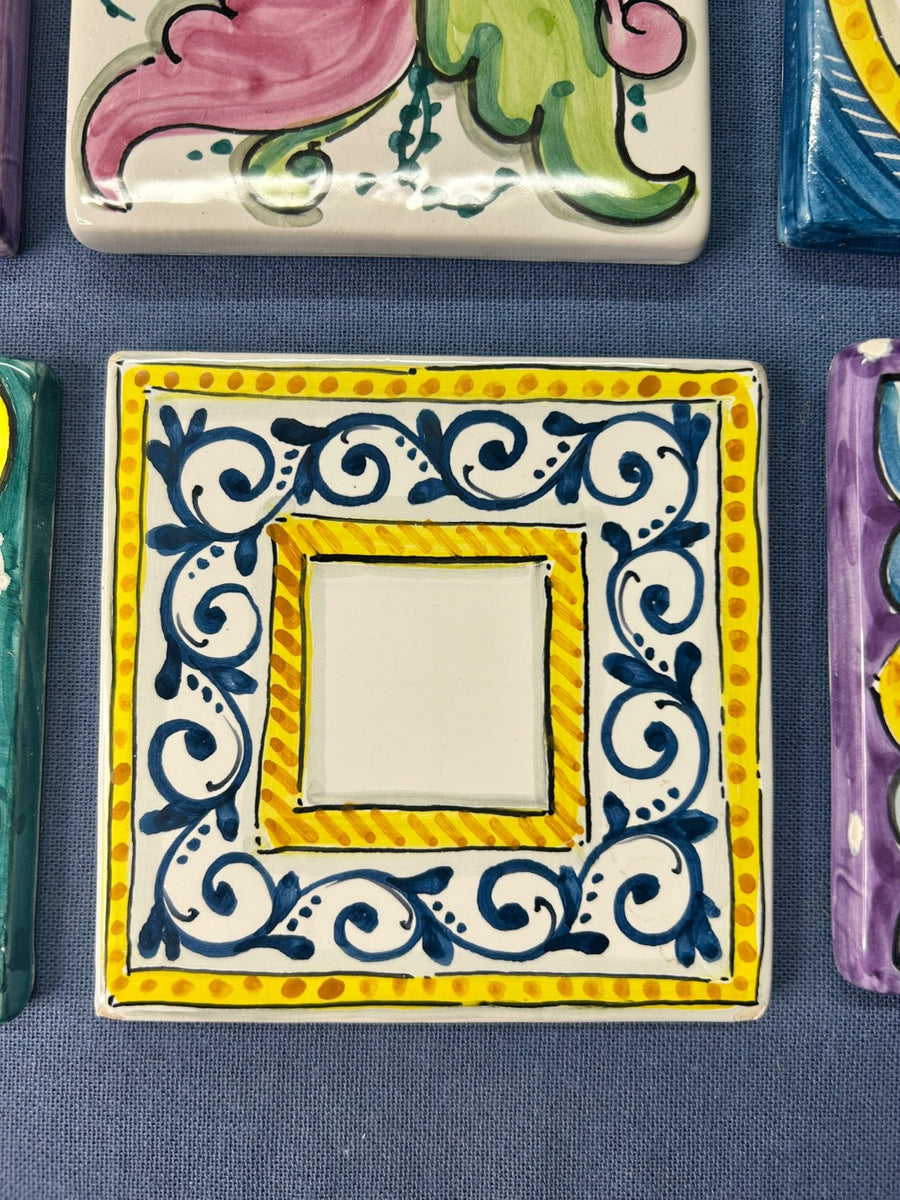Mattonella con la cornice blu e gialla e il centro lasciato bianco.