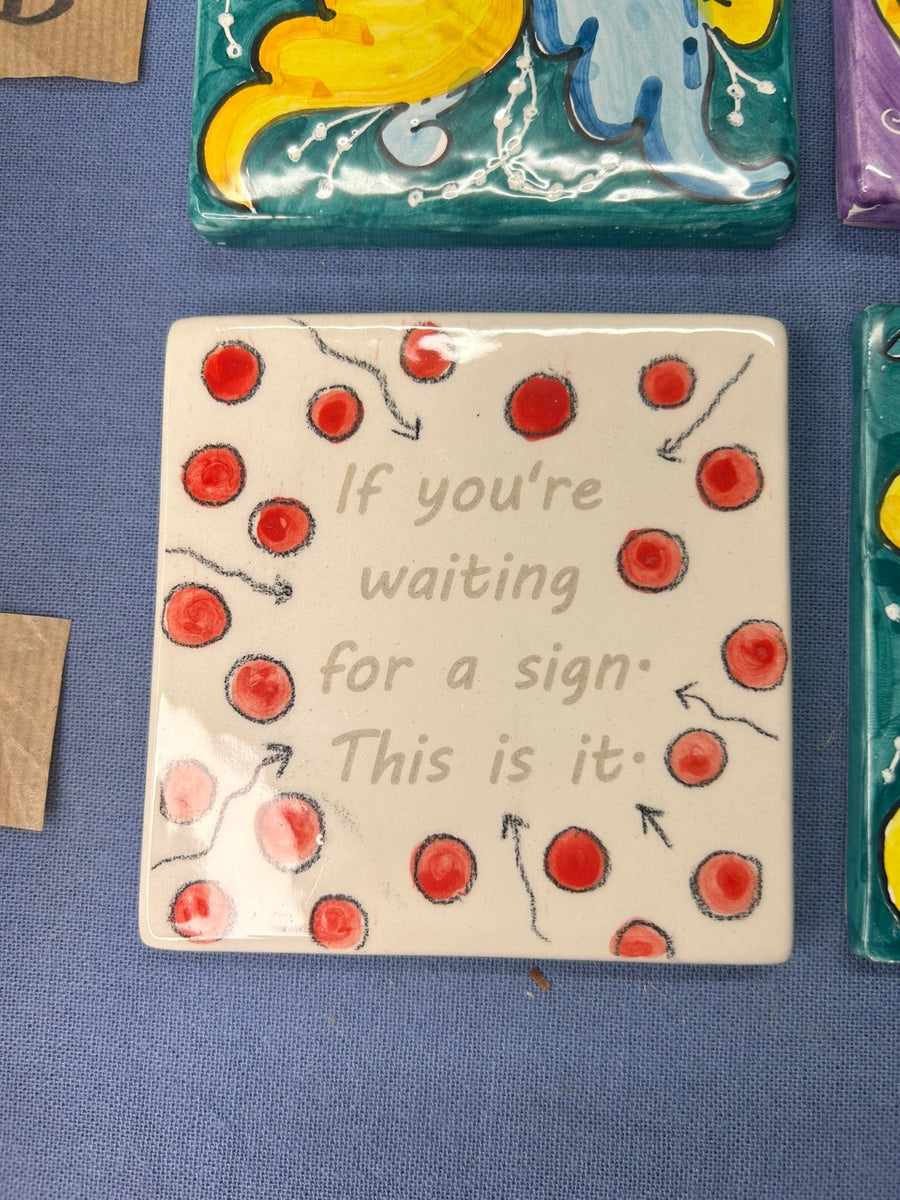 La mattonella «If you're waiting for a sign. This is it.» con i pallini rossi intorno.