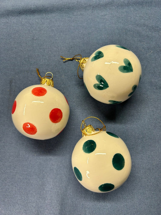 Tre sfere piccole a pois, verdi e arancioni, su un telo blu.