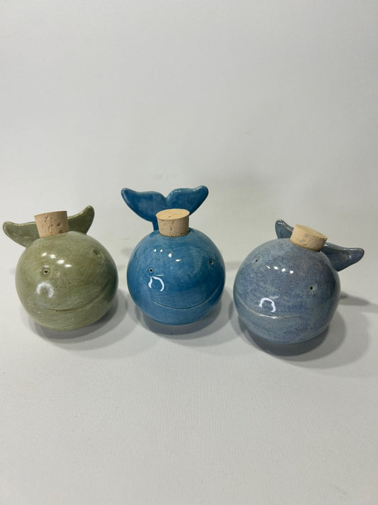 Tre balene di ceramica con il tappo di sughero: una verde, una blu e una blu-grigio.