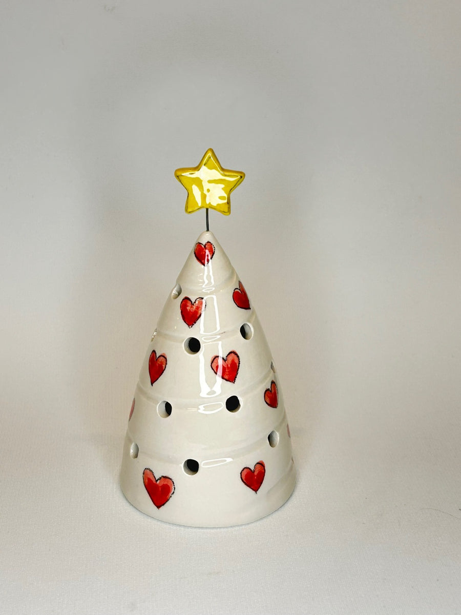 Un alberello bianco con i cuori rossi e i fori da cui esce la luce.