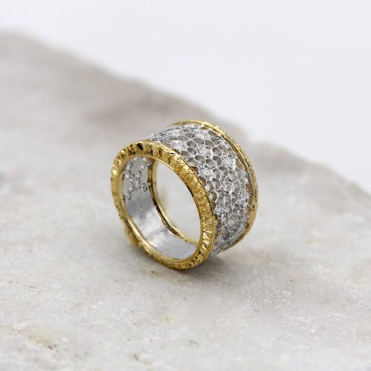 L'anello di tre quarti: la rete traforata in oro bianco fra i due bordi in oro giallo incisi