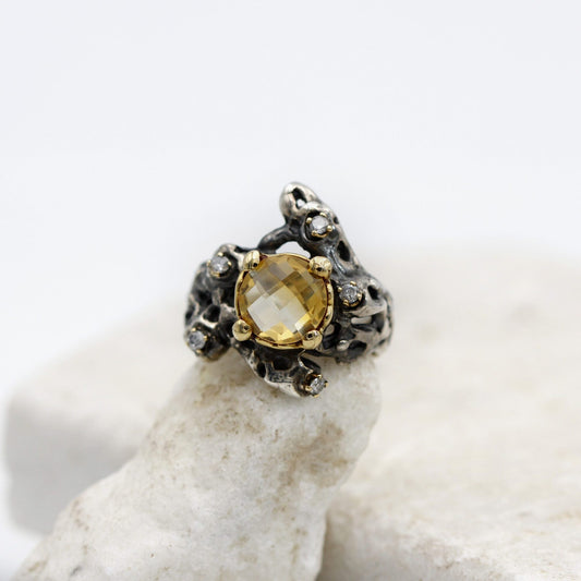 Ripresa frontale appena inclinata: i quattro granelli d'oro che tengono la pietra e i diamanti nei loro granelli sull'argento.