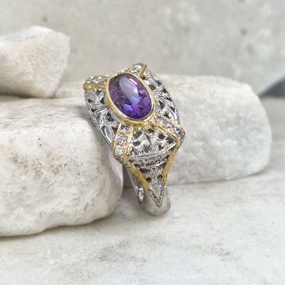 L'anello di tre quarti su una pietra bianca: l'ametista nel castone d'oro sopra il traforo di foglie in argento