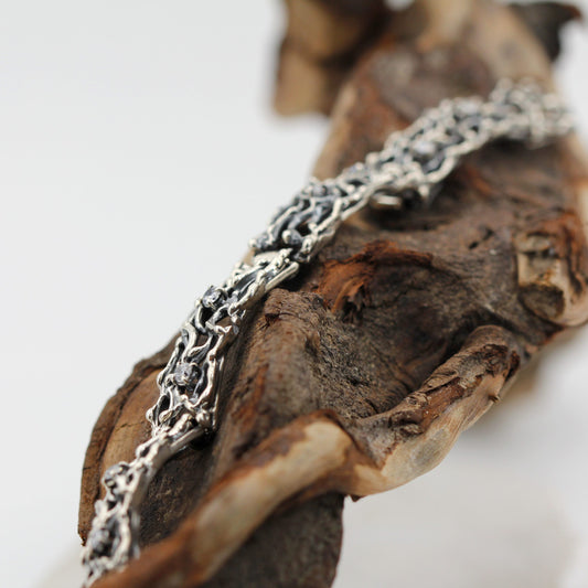 Il bracciale appoggiato su un legno di mare, ripreso di sbieco lungo l'intreccio
