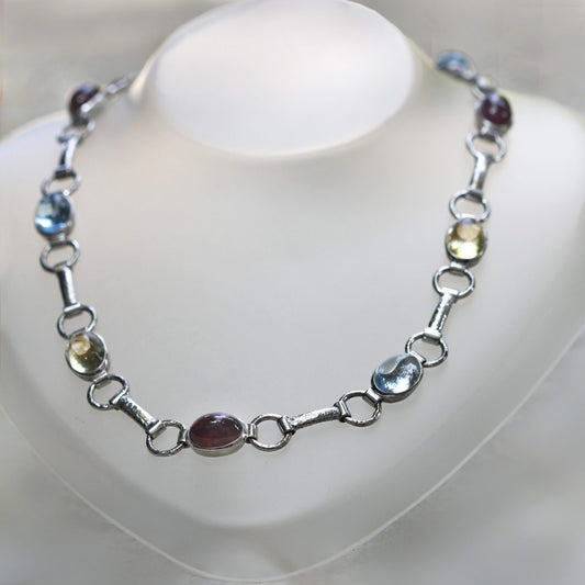 La collana chiusa ad anello su un espositore da collo: la sequenza dei colori si ripete, rosso scuro, azzurro, giallo limone