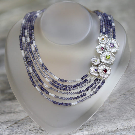 La collana su un espositore da collo: i sei fili di iolite scendono a ventaglio e il gruppo di fiori d'argento appoggia di lato