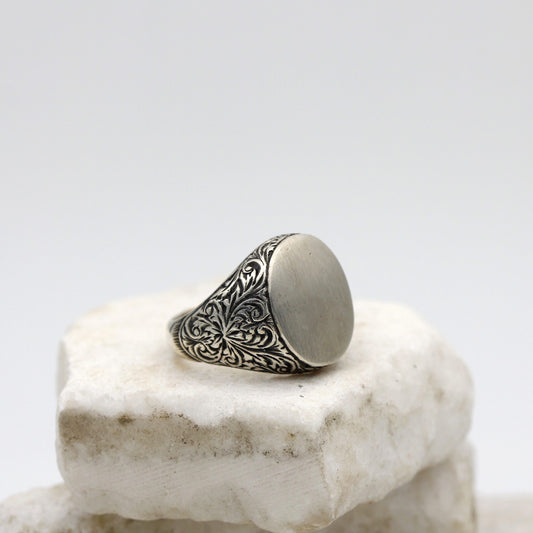 Anello da uomo in argento con la testa ovale liscia e le spalle incise a bulino, veduta di tre quarti