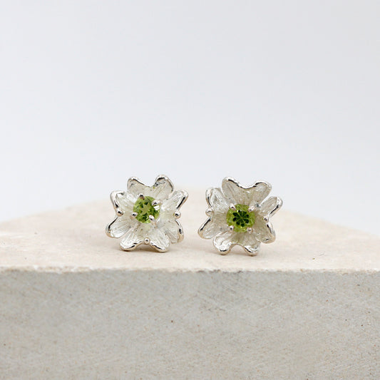 I due orecchini a fiore visti di fronte, il peridoto tondo al centro di ciascuno