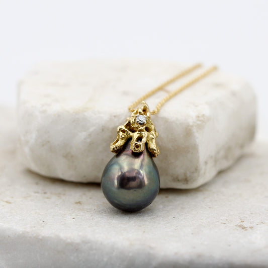La perla a goccia e la calotta d'oro appoggiate a una pietra chiara