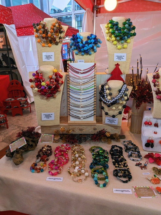 Il banco al mercatino: collane di resina sugli espositori e braccialetti stesi sul tavolo