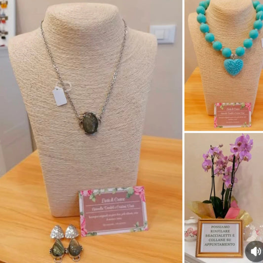 Collana con cabochon ovale grigioverde in castone d’argento e orecchini abbinati, accanto al cartellino della bottega
