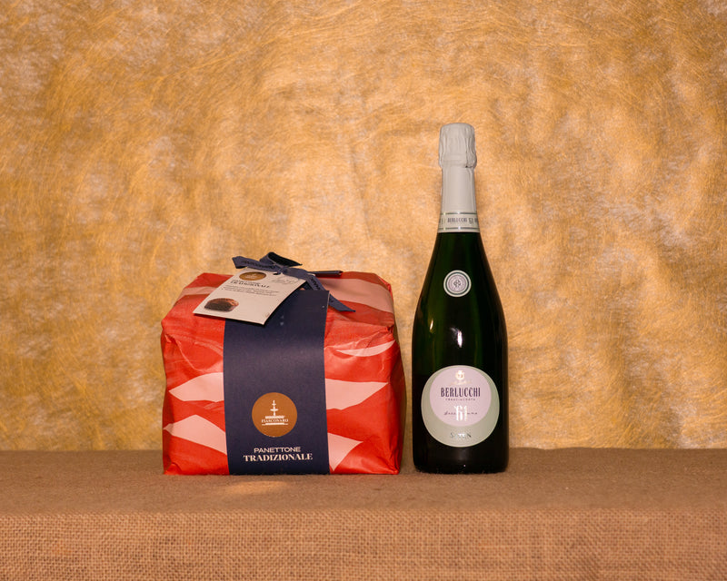 I 2 prodotti del cesto «Brindisi d’Autore» disposti sul fondo di juta: Panettone tradizionale Fiasconaro e Franciacorta Satèn Berlucchi ’61.