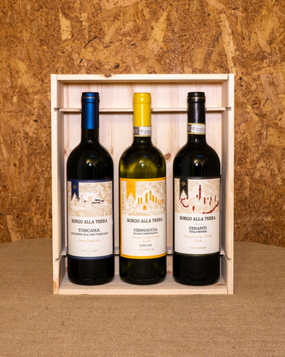 Le tre bottiglie nella cassetta di legno aperta: Vernaccia di San Gimignano DOCG, Governo all’uso toscano IGT e Chianti Colli Senesi DOCG.