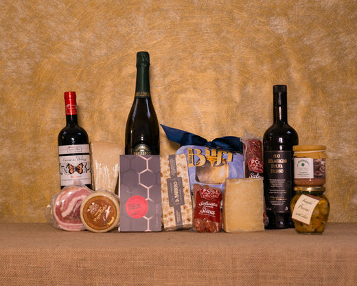 I 14 prodotti del cesto «Scrigno delle Feste» disposti sul fondo di juta, fra cui Valdobbiadene Extra Dry Bellussì, Bolgheri DOC Rosso diVaira e Panettone artigianale Biffi, e gli altri.