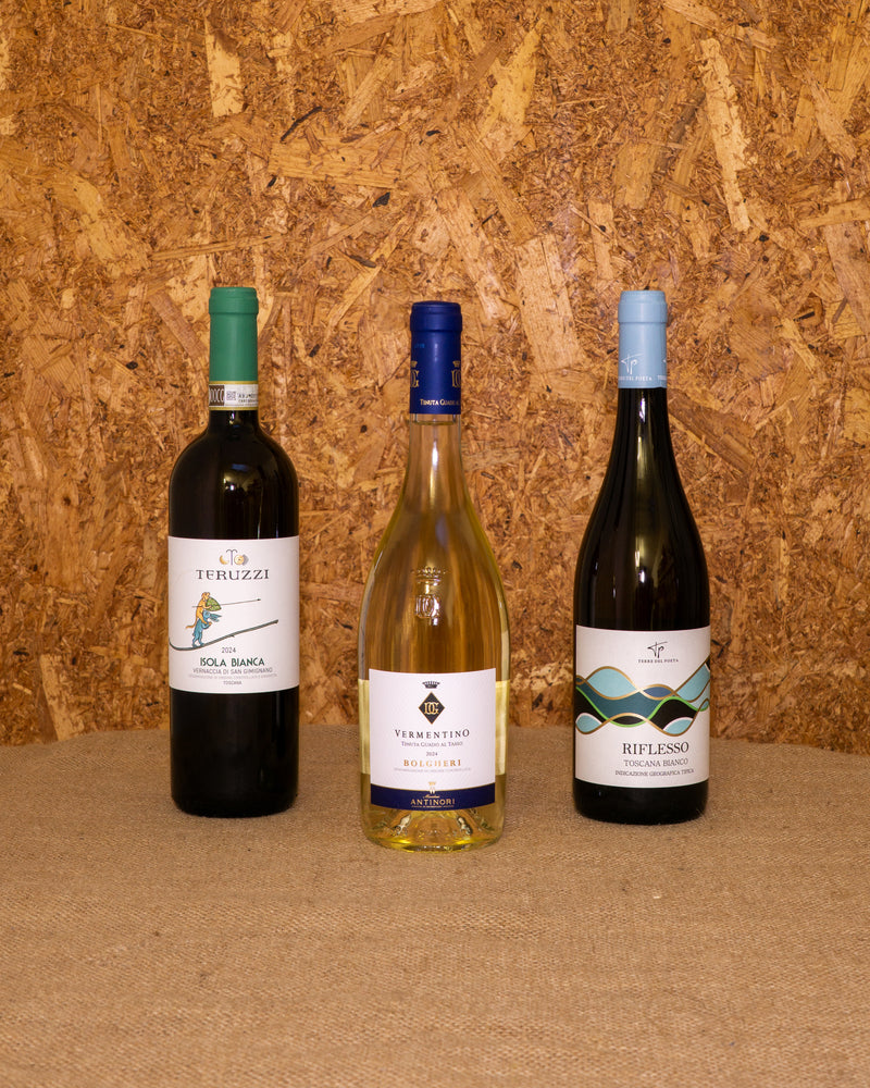 Le 3 bottiglie della selezione «Toscana Bianca» in piedi davanti al fondo del set: Colline Albelle in Bianco, Vernaccia Isola Bianca e Vermentino Bolgheri Guado al Tasso.