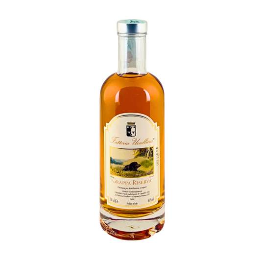 Bottiglia di Grappa Riserva della Fattoria Uccelliera, distillato ambrato in bottiglia slanciata, su fondo bianco
