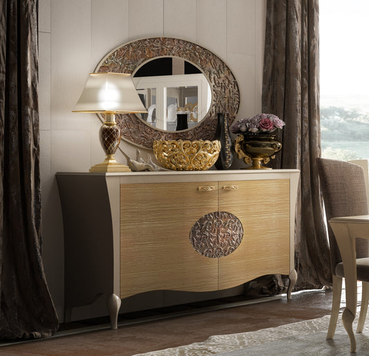 La credenza 861 sotto la specchiera 1636: il fronte nocciola, il tondo intagliato al centro e le gambe corte in fuori