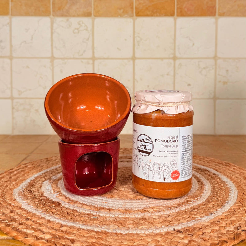 Il fornellino rosso di terracotta con la ciotola sopra, accanto al vasetto di pappa al pomodoro