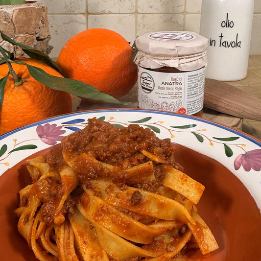 Tagliatelle condite col ragù d'anatra, con arance intere e il vasetto sullo sfondo