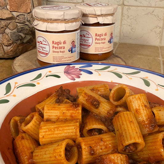 Due vasetti dietro un piatto di rigatoni conditi col ragù di pecora