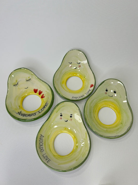 Cinque portanoccioli verdi a forma di avocado, con il foro giallo al centro, visti dall'alto.