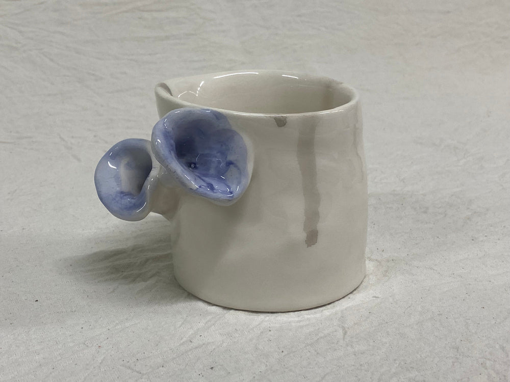 White tumbler with a blue flower, without a handle