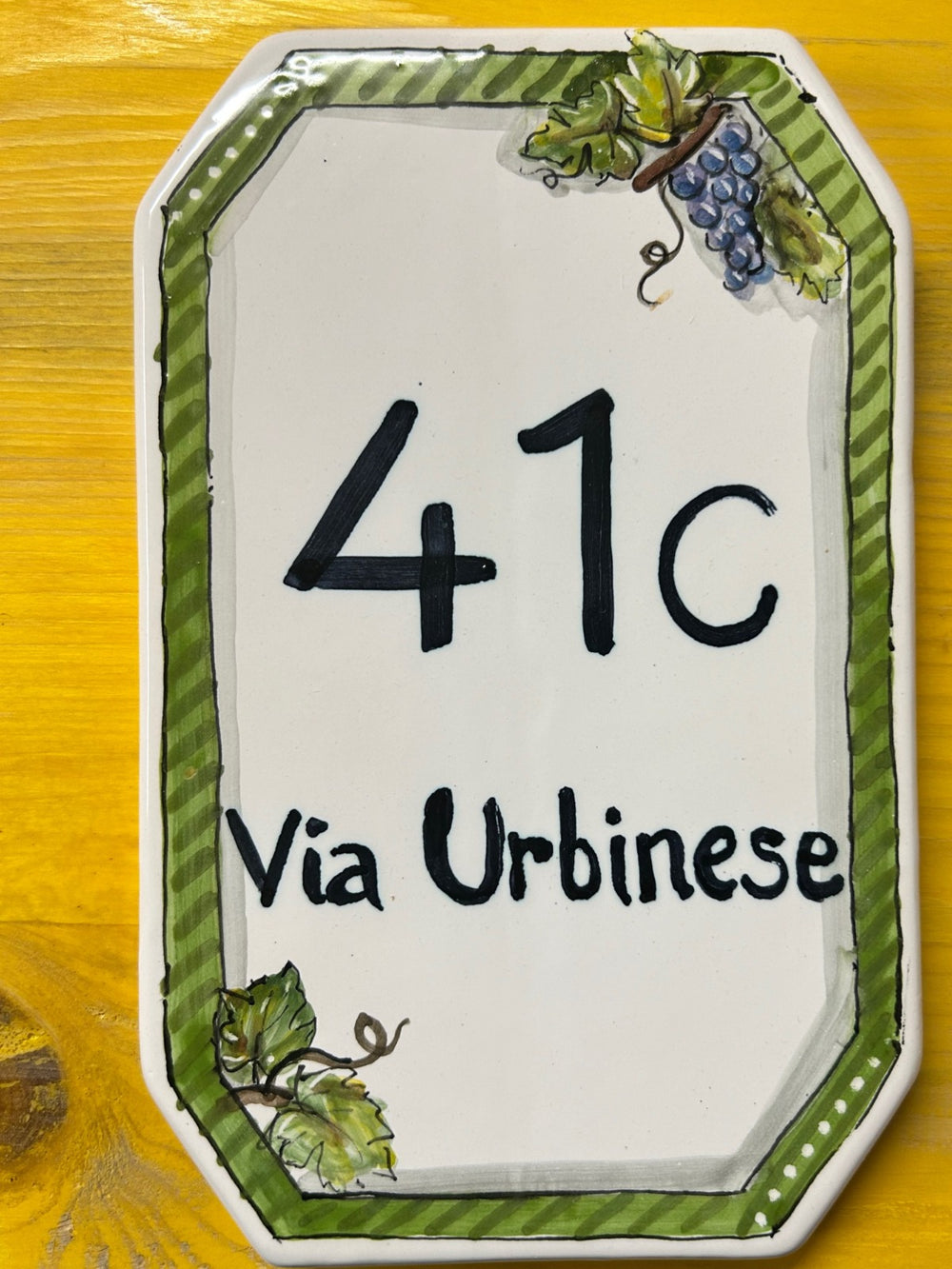 Targa rettangolare con il numero 41C e «Via Urbinese», cornice di foglie di vite e grappoli d'uva.