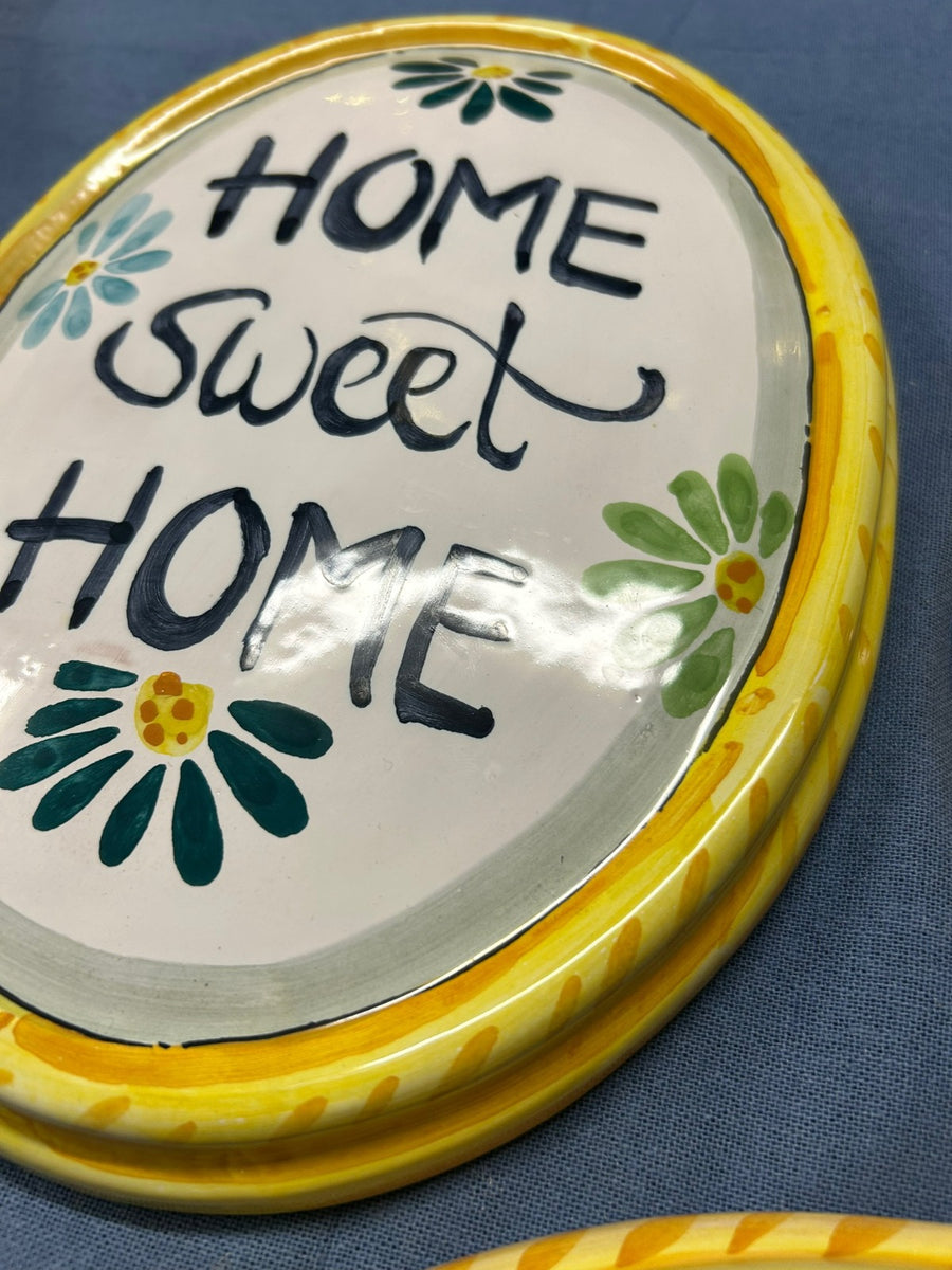 Dettaglio della targa «Home sweet home» con le margherite verdi.