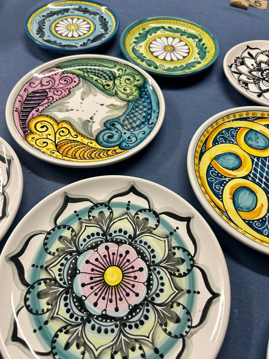Piatti dipinti a mano su un telo blu, con mandala, girandole e fiori.