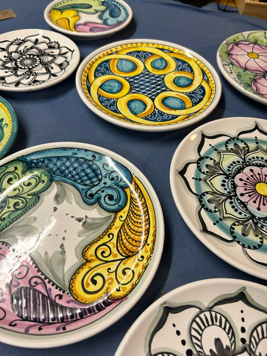 Gli stessi piatti visti di scorcio, con decori gialli, verdi e rosa.