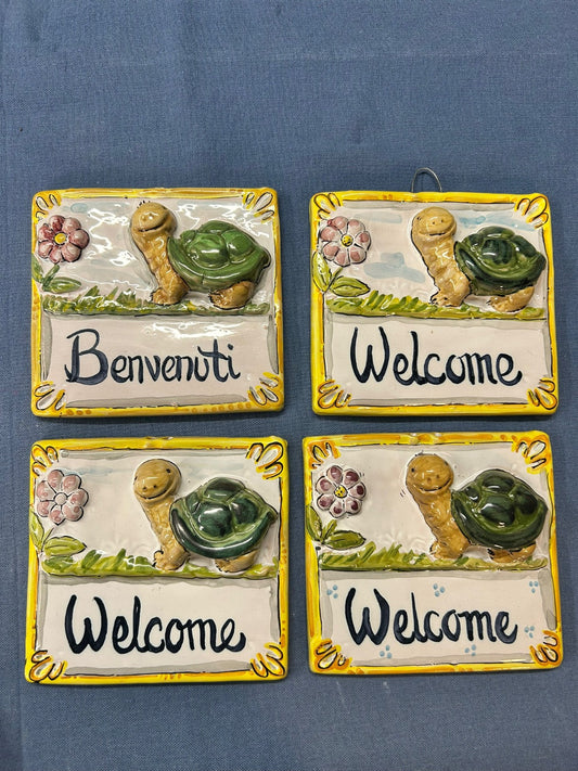 Quattro pezzi uguali affiancati, con le scritte «Benvenuti» e «Welcome».