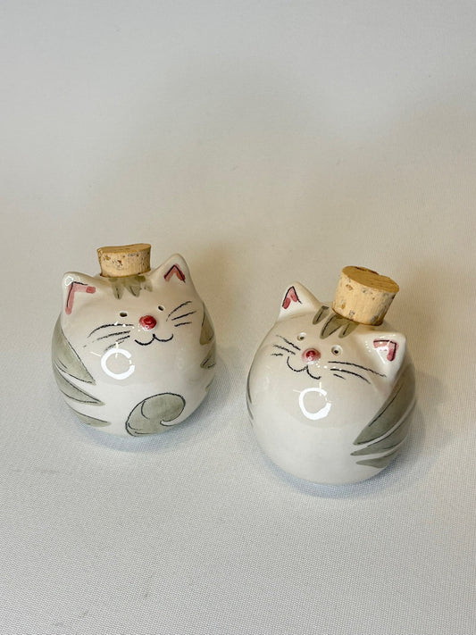 Due gatti di ceramica con il tappo di sughero, i baffi sottili e le guance rosa.