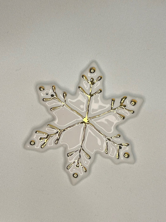 Un fiocco di neve bianco con i rametti e i puntini dipinti in oro.