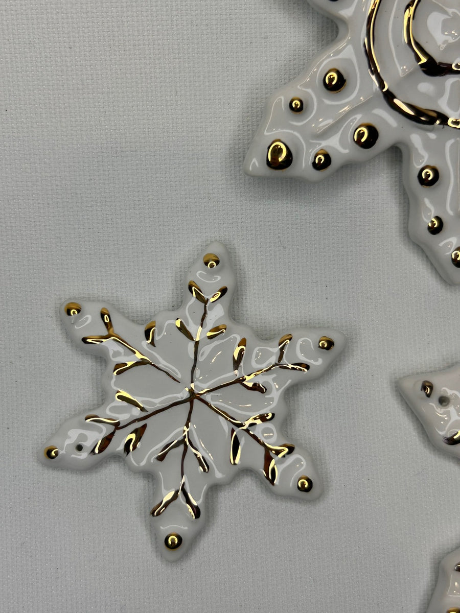 Un fiocco di neve visto dall'alto, accanto a un altro pezzo decorato in oro.