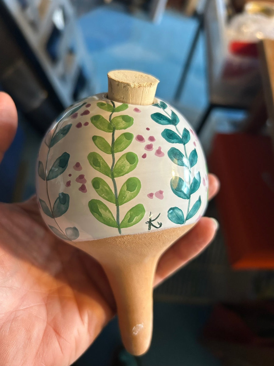 Un pezzo bianco con i rametti verdi e i fiorellini rosa, tenuto in mano.