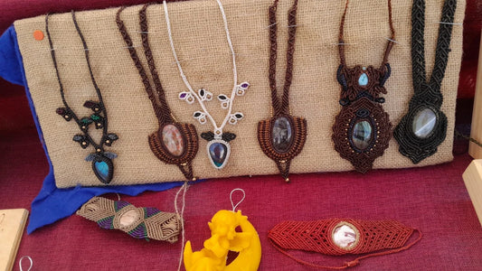 Pendenti in macramè nero e marrone con le pietre chiare appesi sulla juta, e sotto due bracciali a fascia con la pietra al centro