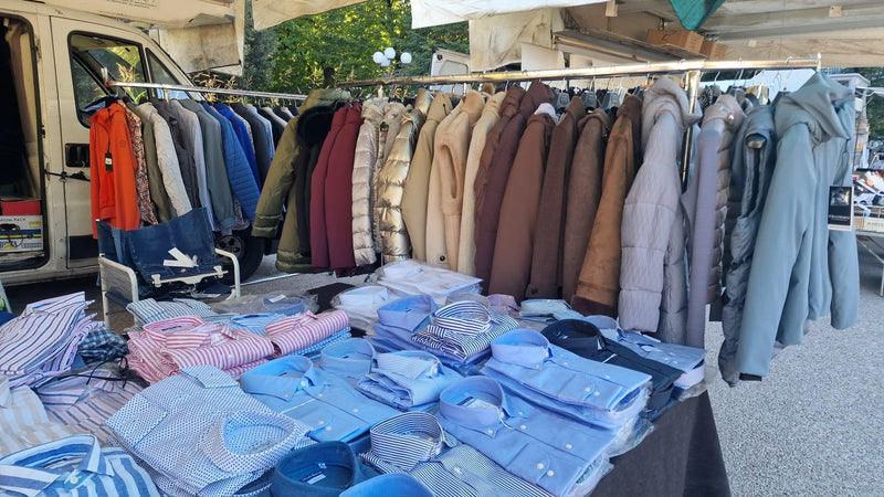 Le camicie piegate sul tavolo e la fila di cappotti e piumini appesi