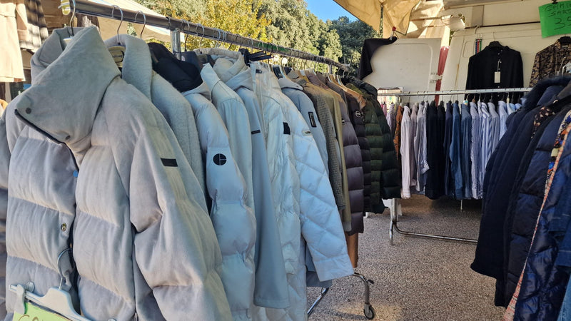 Piumini e giacche appesi in fila sotto il tendone