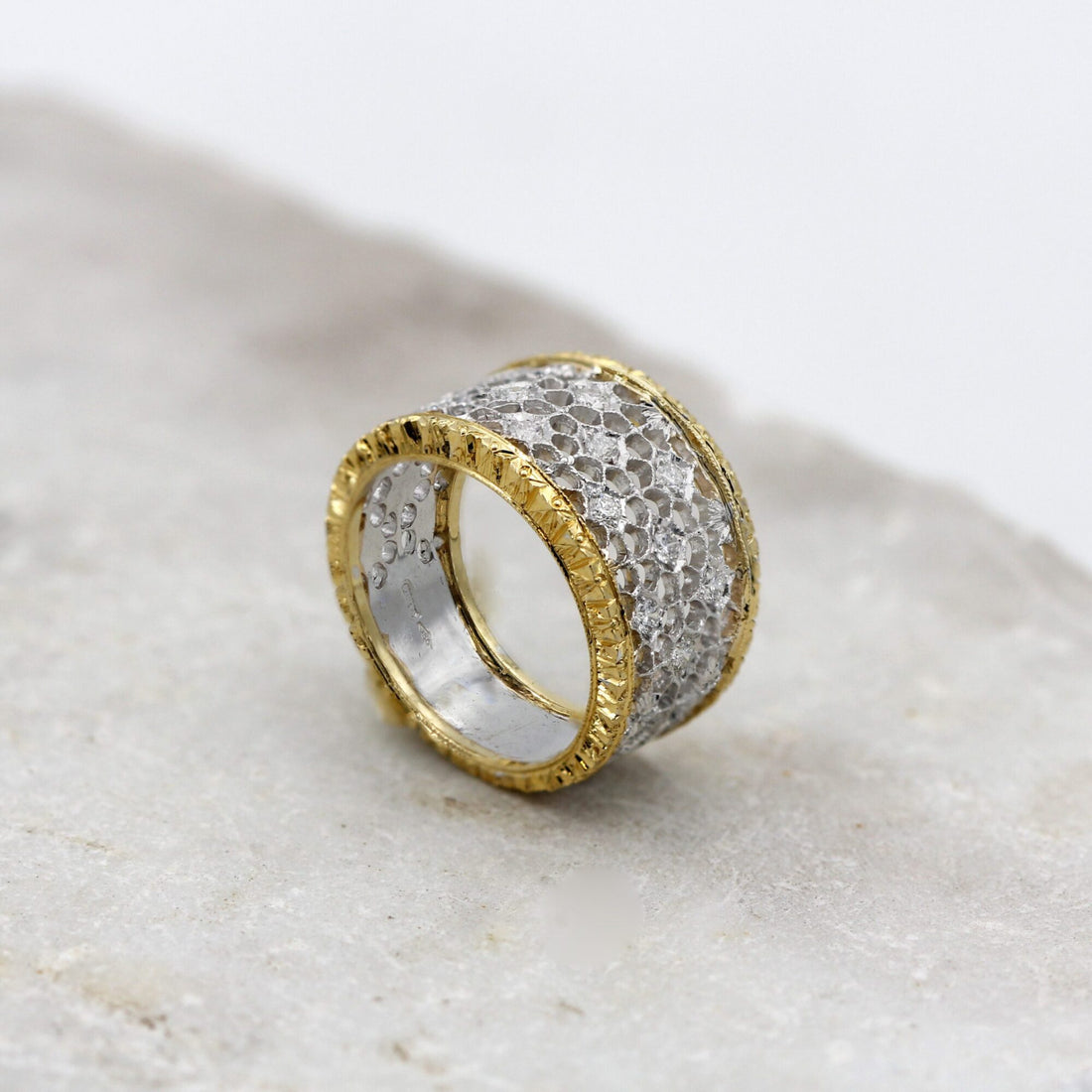 L'anello di tre quarti: la rete traforata in oro bianco fra i due bordi in oro giallo incisi