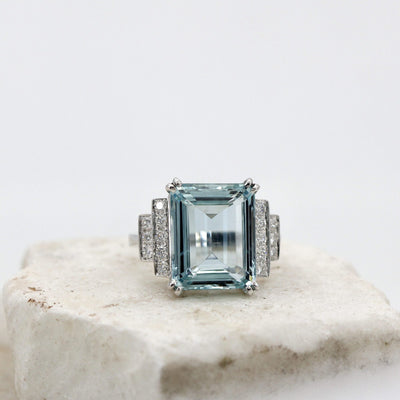 The ring from the front on a block of white stone, the table of the aquamarine in full light