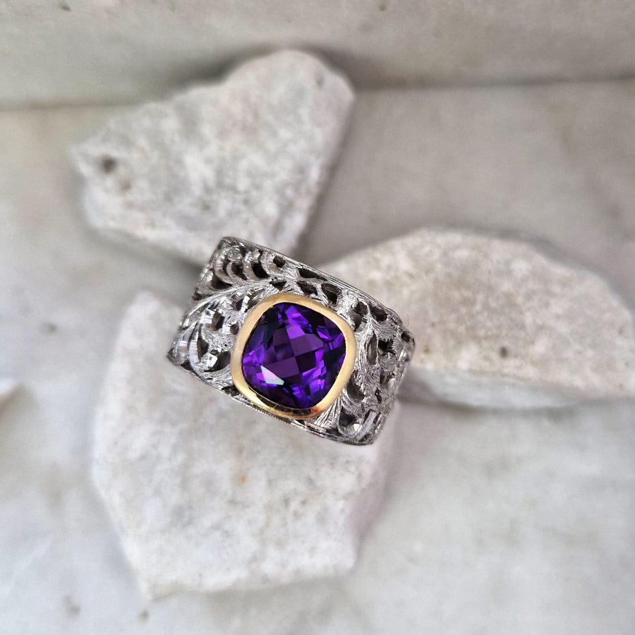 The piece from above: the cushion-cut amethyst and the acanthus scrolls cut open around the bezel