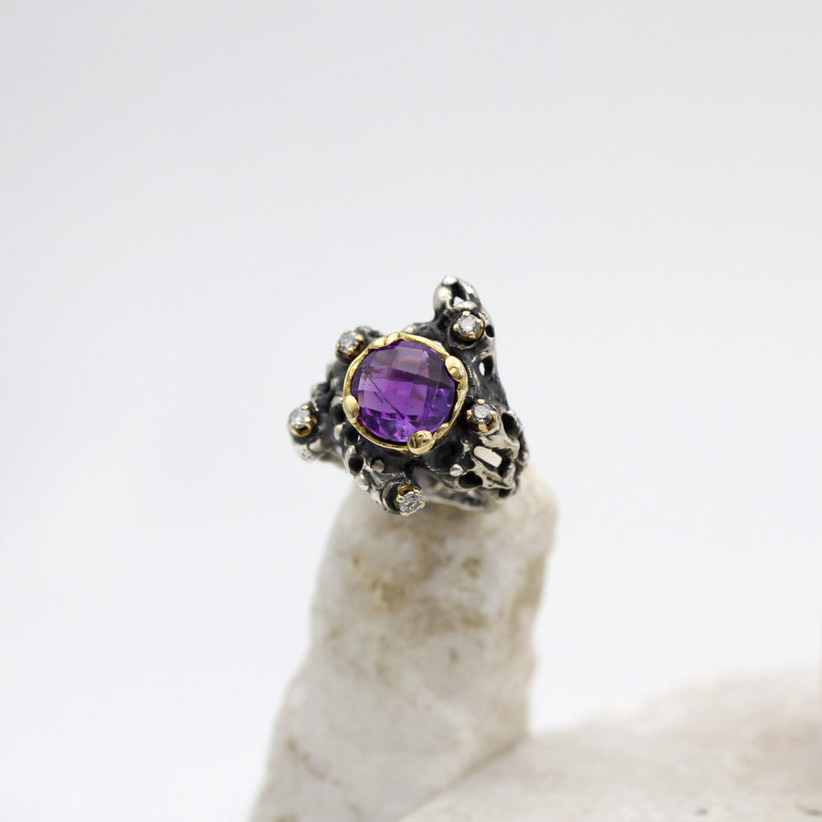 The whole ring from the front: the cross-shaped outline of the shoulders around the amethyst.