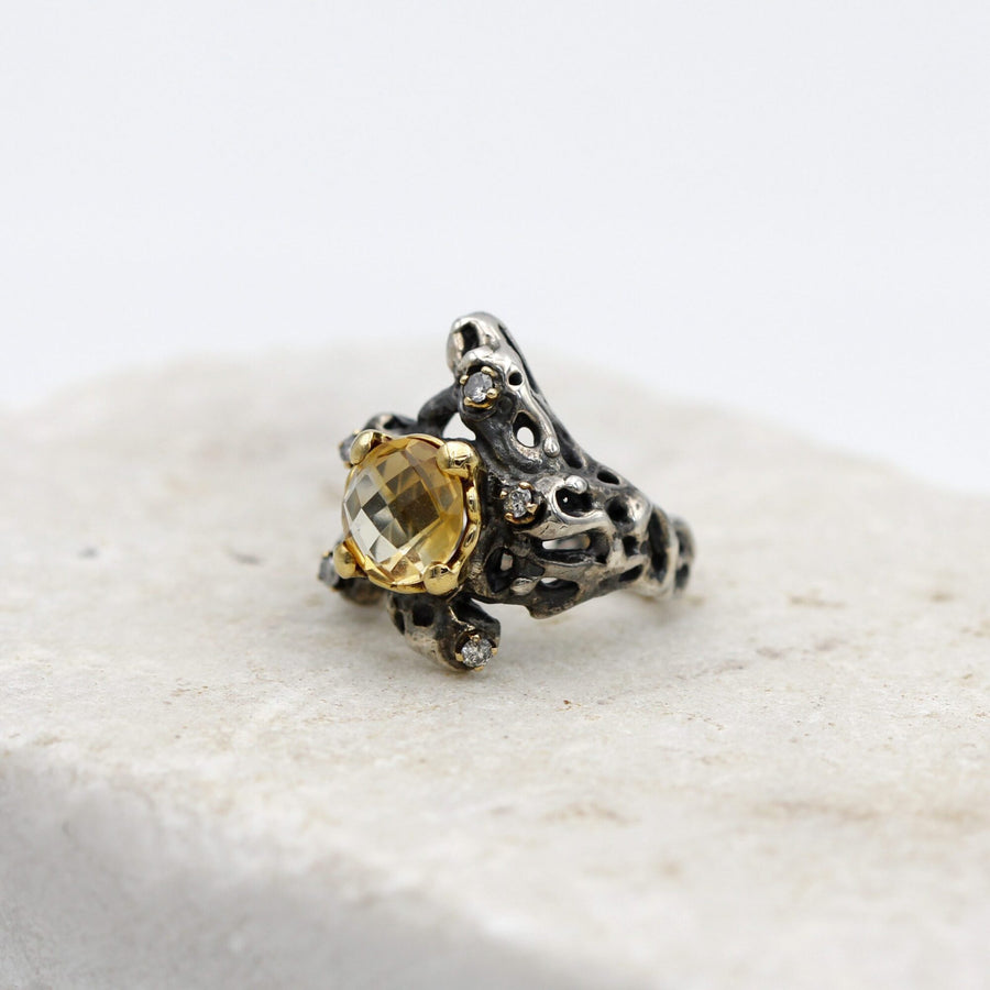 Three-quarter view from the left: the gold bezel projects from the silver body and how high the stone rises is visible.