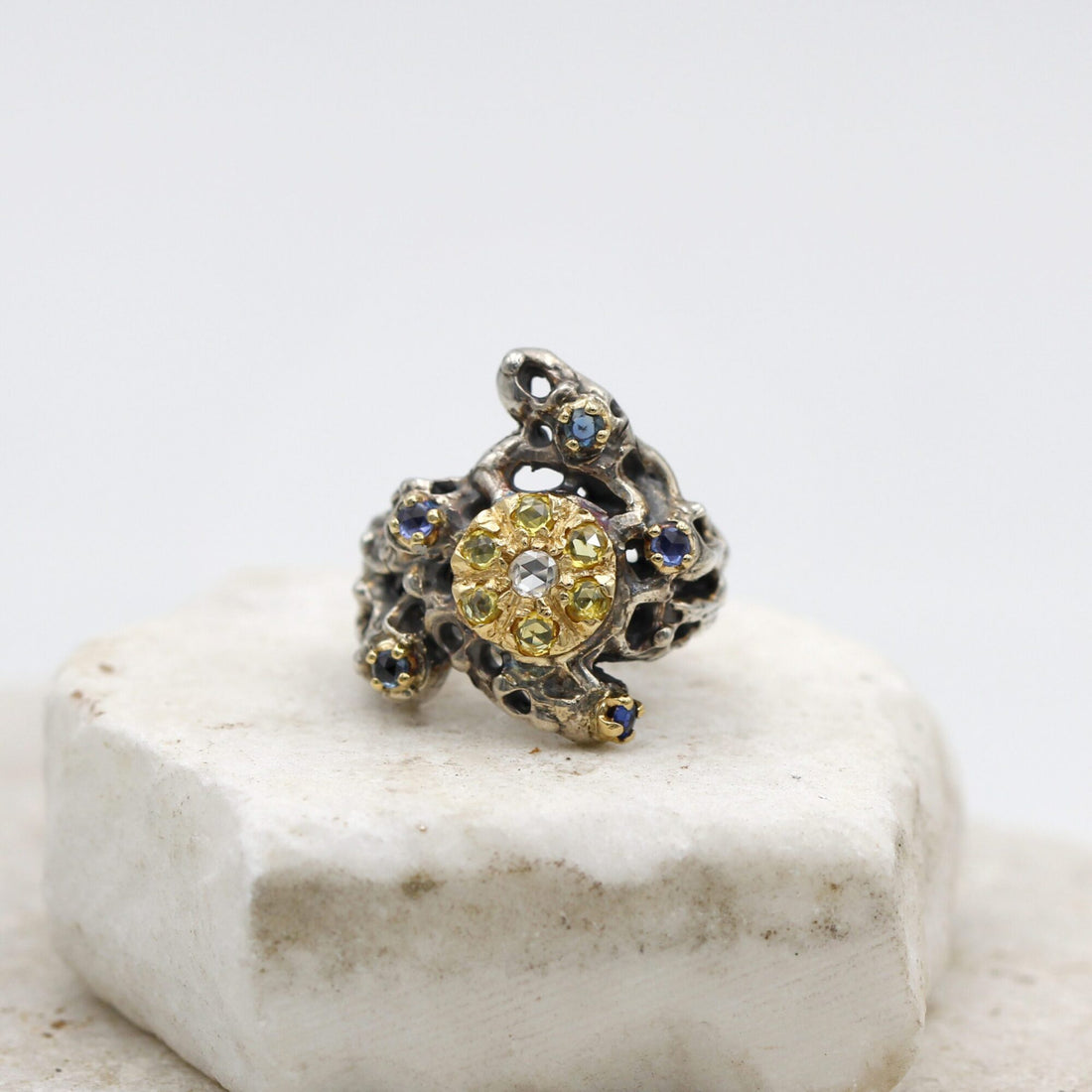 The ring seen from above: the gold disc with the seven yellow sapphires around the diamond, on the pierced silver mass