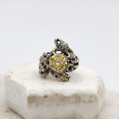 The ring seen from above: the gold disc with the seven yellow sapphires around the diamond, on the pierced silver mass