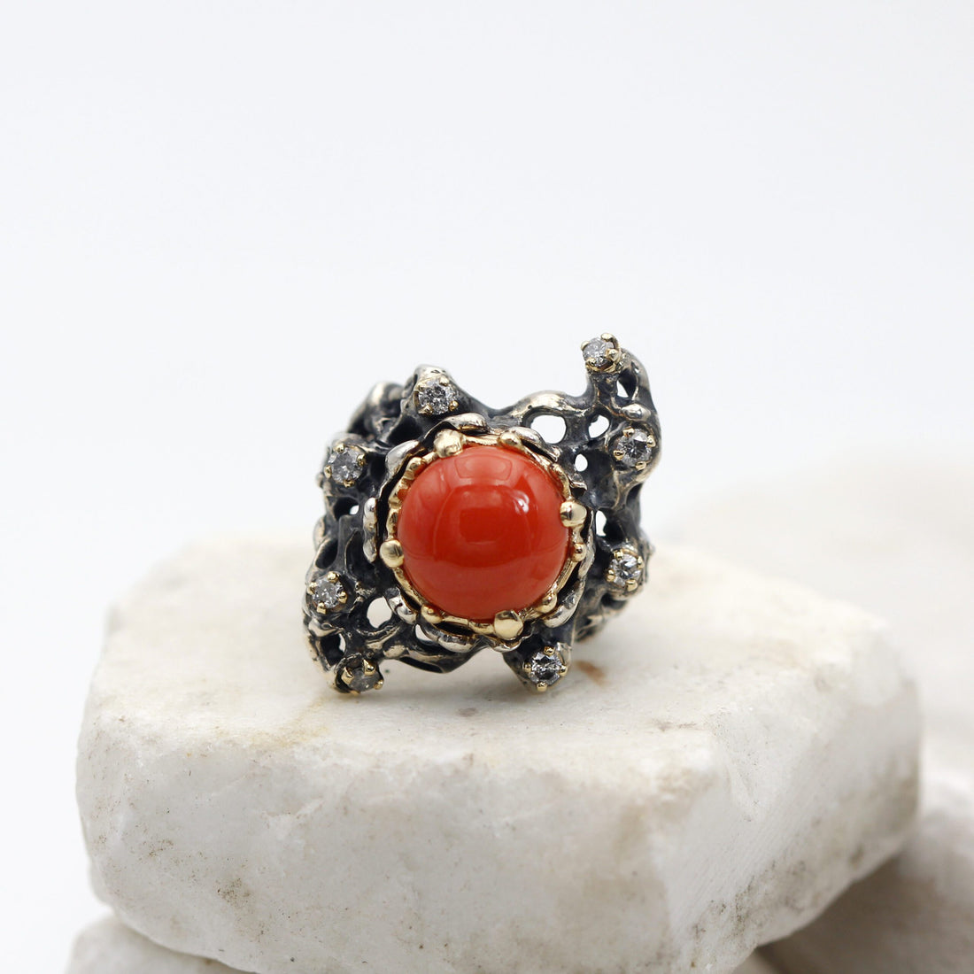 The round coral in the gold bezel, from the front, on the burnished openwork silver